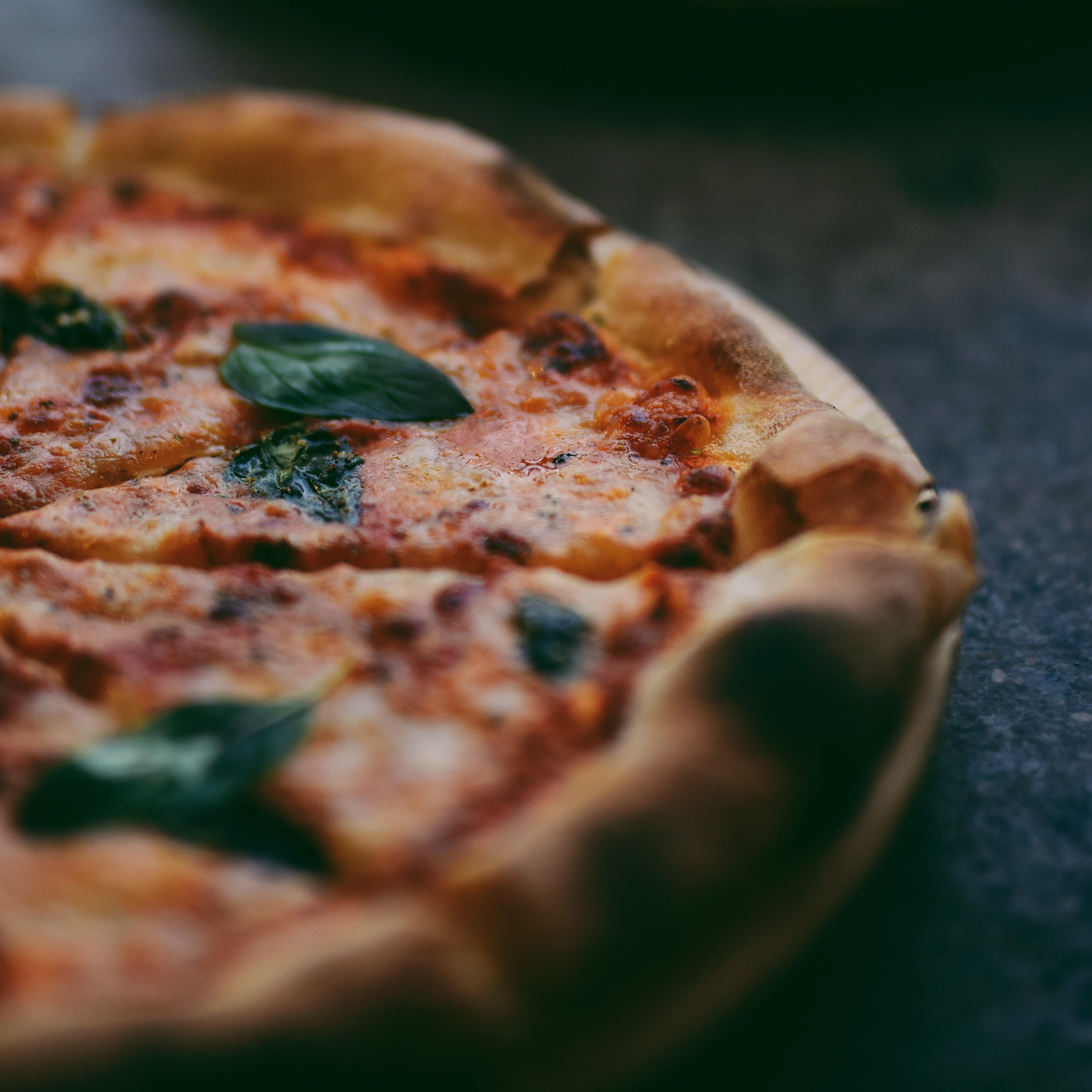 margarita pizza with basil and blurred pizza in background